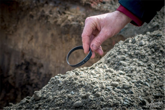 black wristband being placed beneath the earth