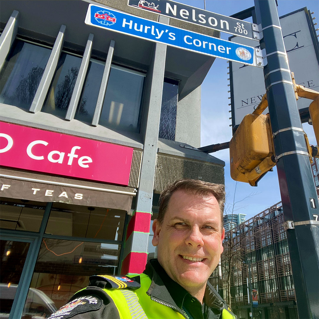 Al Pruden smiling in front of the new Hurly's Corner sign
