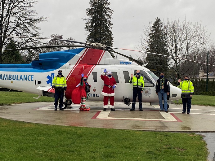 Santa, elf, paramedics and Helijet CEO by a BCEHS air ambulance helicopter