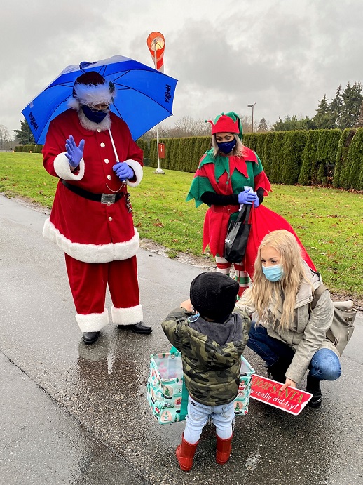 Santa and elf give a gift to a child outside BC Children's Hospital