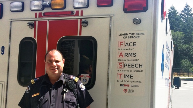 Paramedic stands next to ambulance with ACT FAST stroke awareness decal