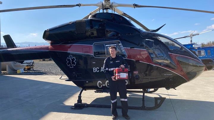 Critical care paramedic with blood supplies next to BC Ambulance helicopter
