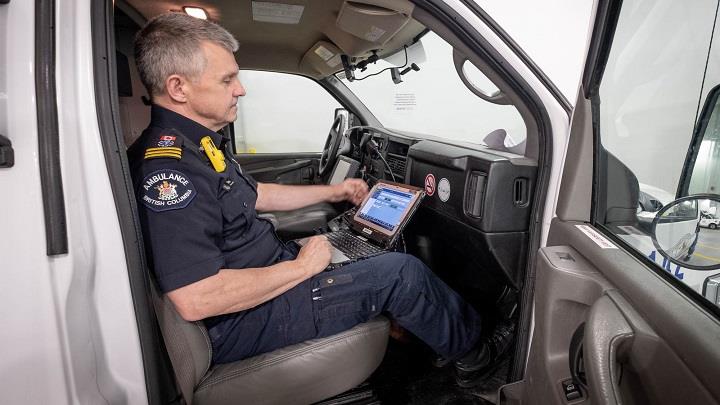 Paramedic uses laptop in ambulance