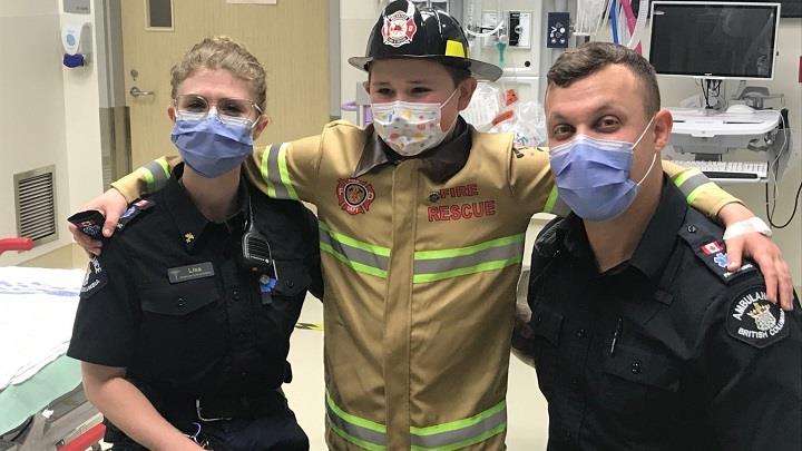 Two paramedics with a boy dressed as a firefighter