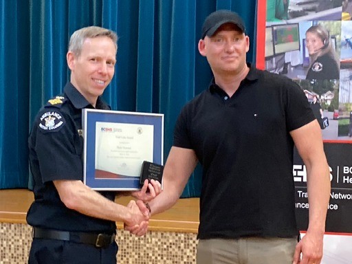 Doctor in BC Ambulance uniform presents certificate to Marc Downes